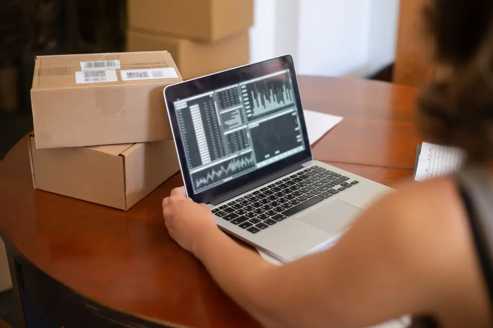 A laptop showing sales charts on a table beside parcels ready to send