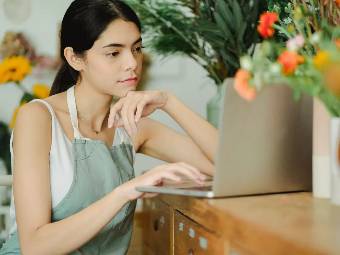 A florist working on a laptop in her shop between customers